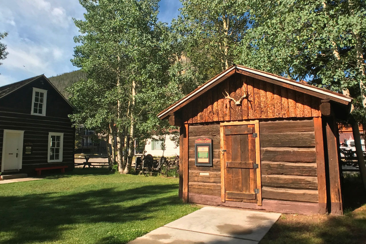 Tiny cabin with antlers mounted above the door and aspens in the background