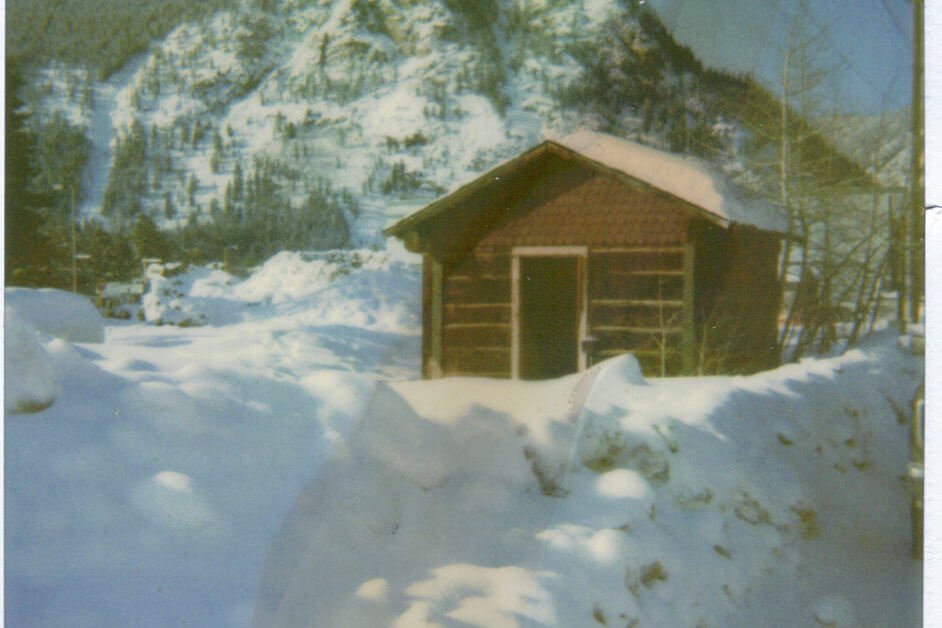 Old color photo of Trapper's Cabin covered in snow at its original location.