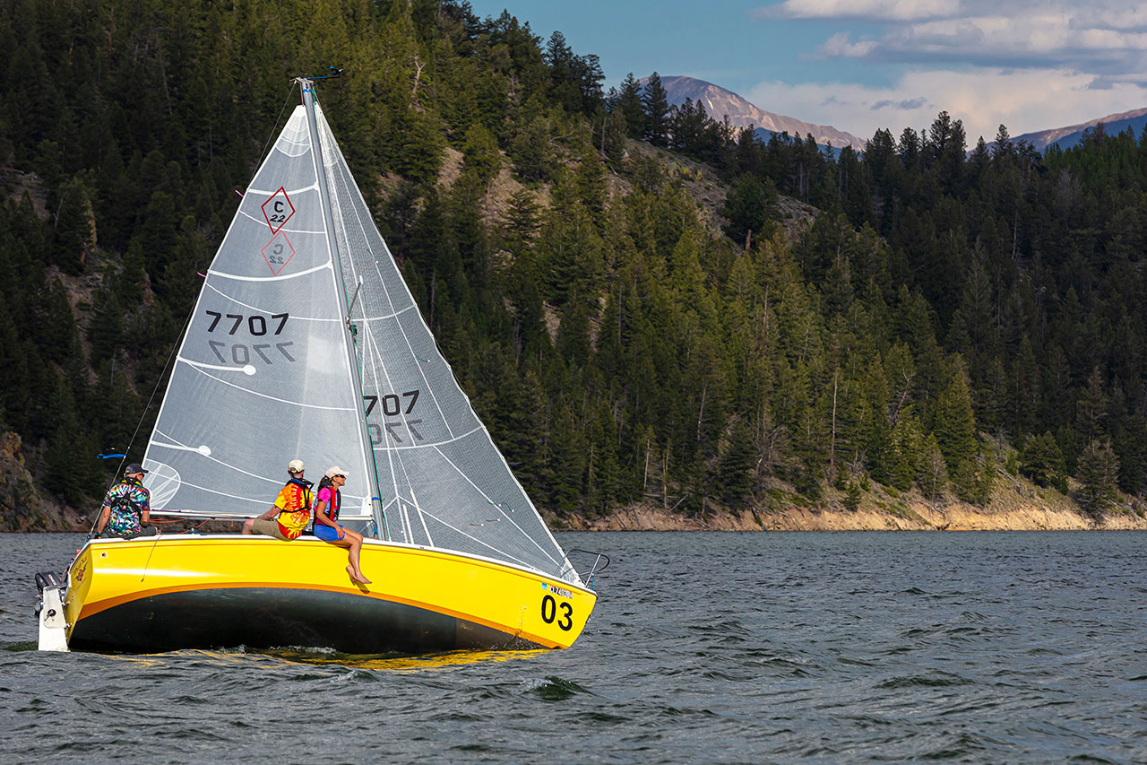 Three people relaxing on yellow sail boat on Lake Dillon.