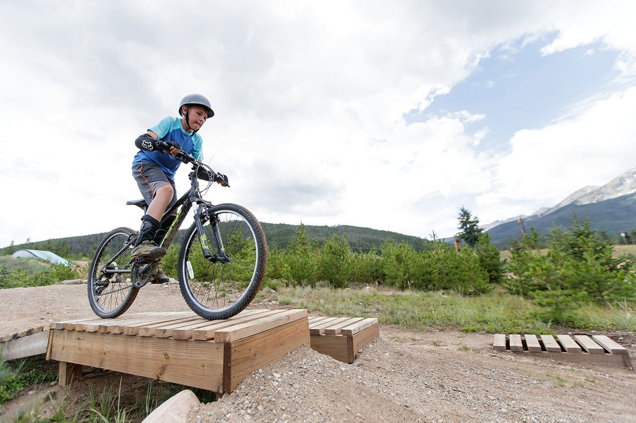 Boy riding mountain bike over a feature.