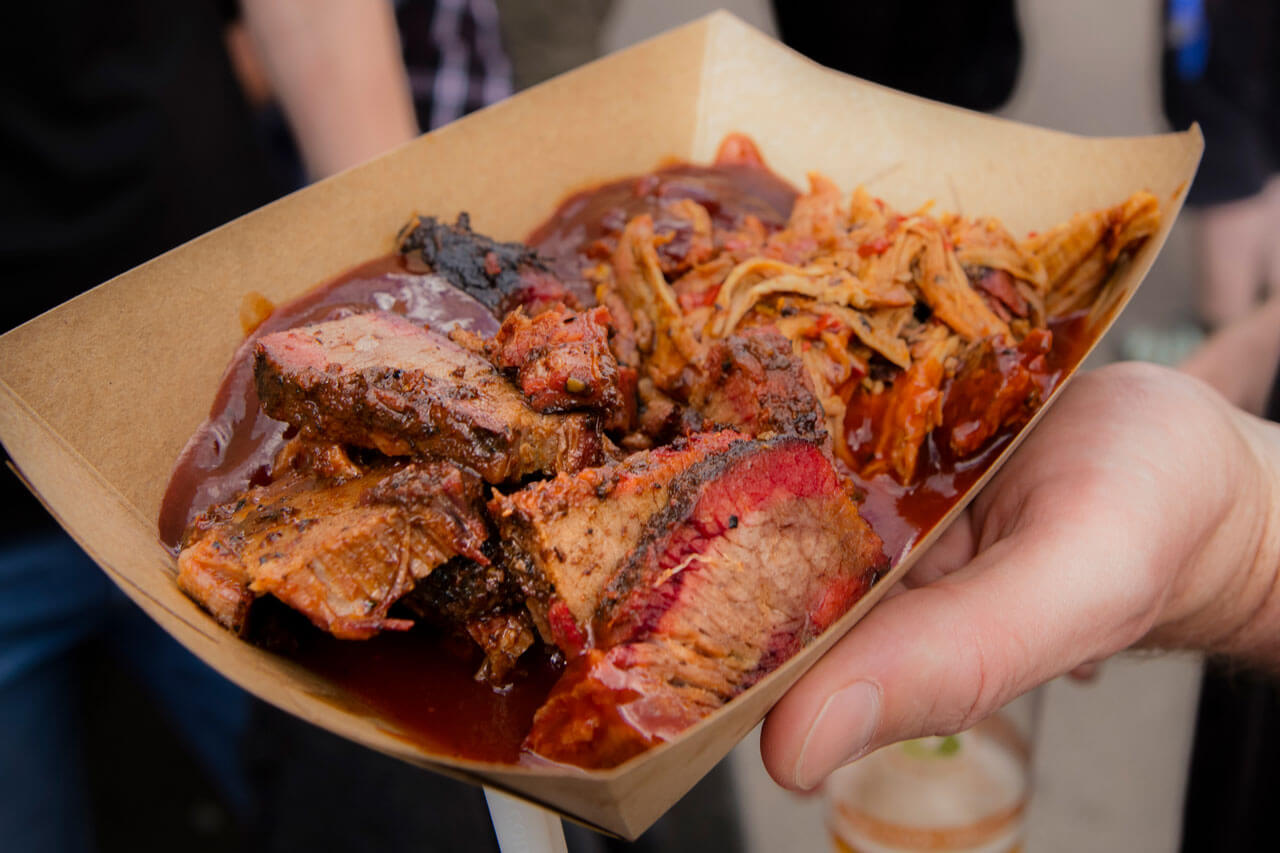 Close-up of beef brisket and pulled pork served in a cardboard dish.