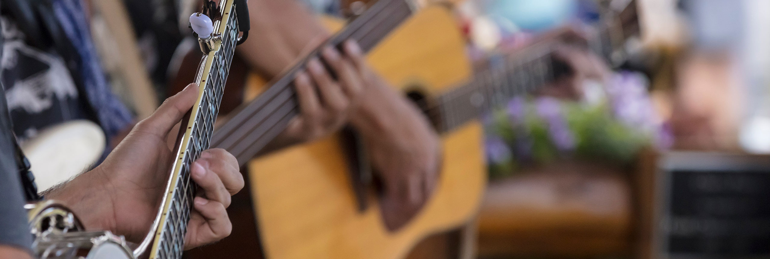 Closeup of two people playing guitars.