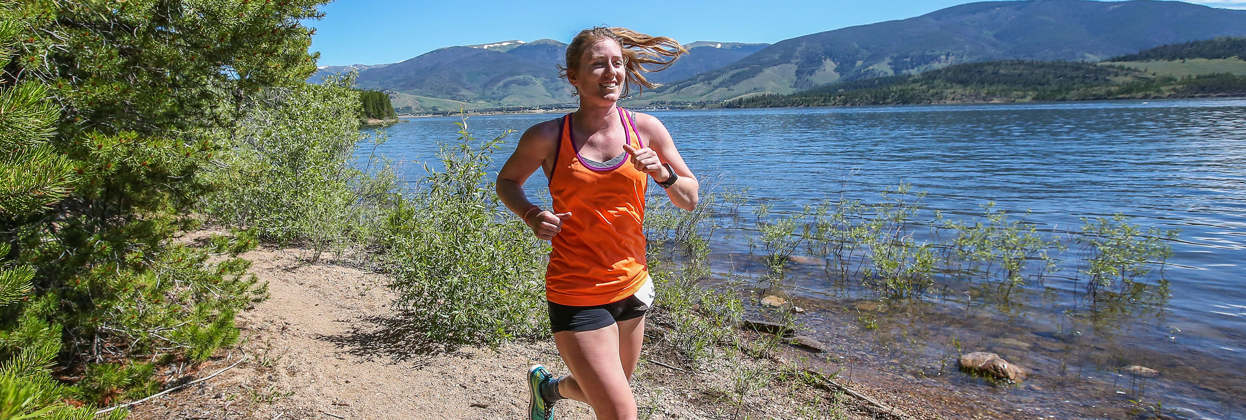 Woman running on trail right next to Dillon Reservoir water