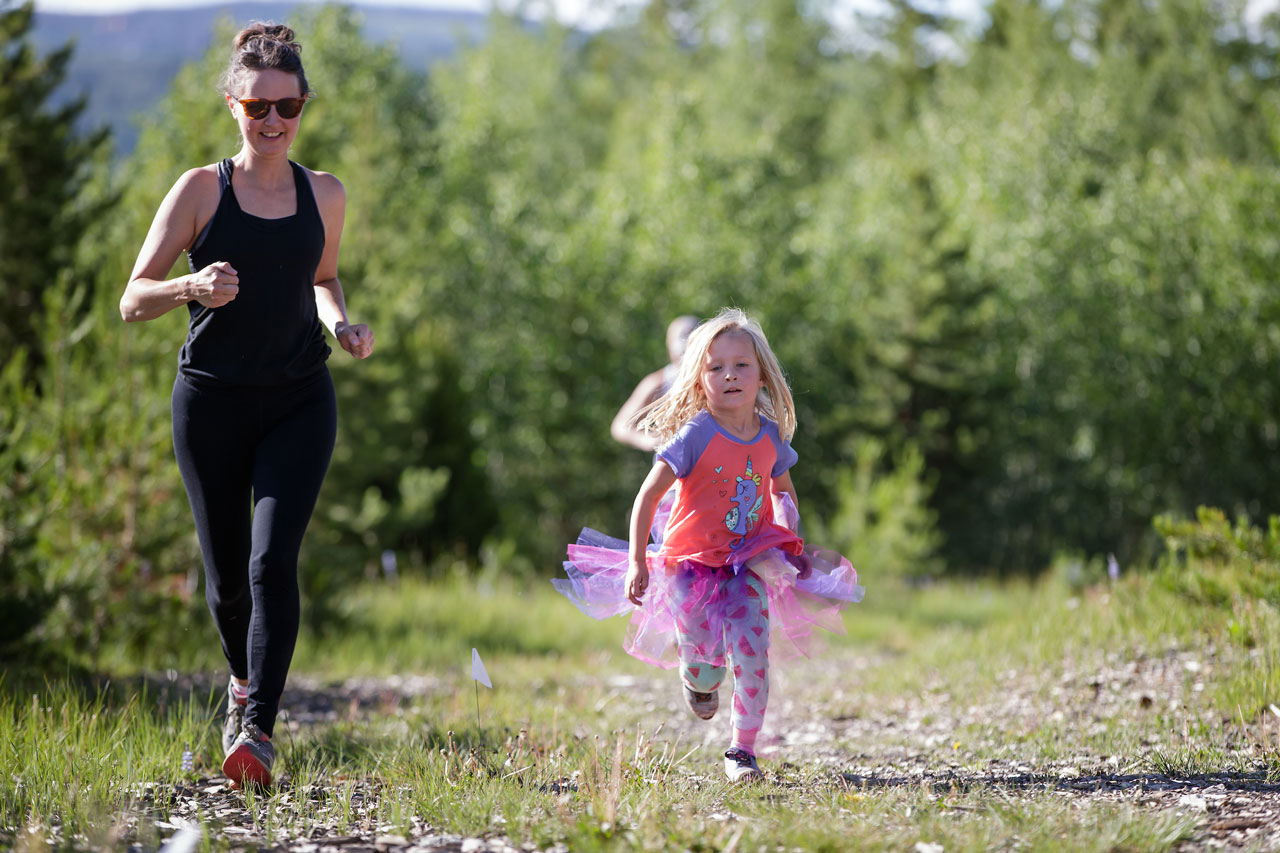 A woman and young girl who is wearing a tutu running on a trail.