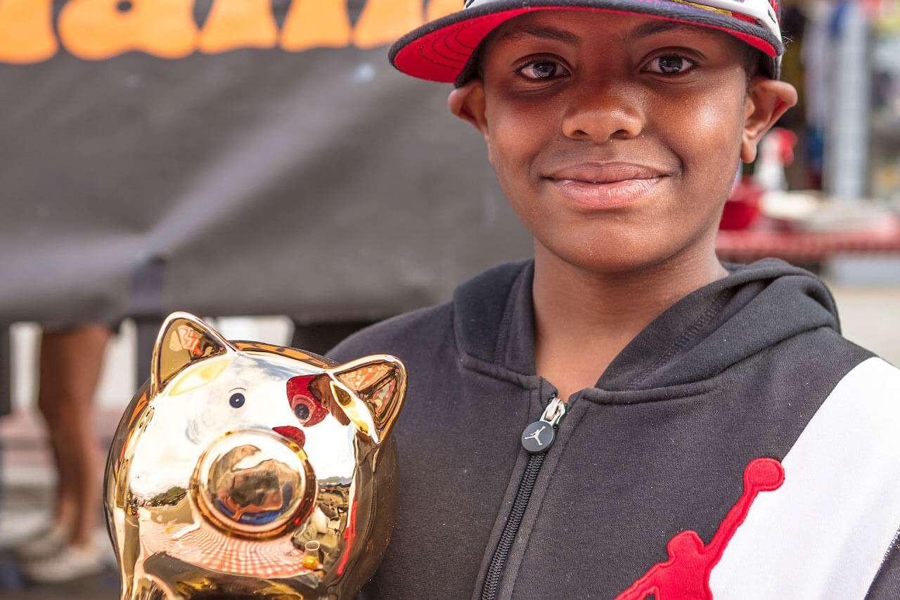 Close-up of boy in a ball cap holding a pig-shaped trophy.