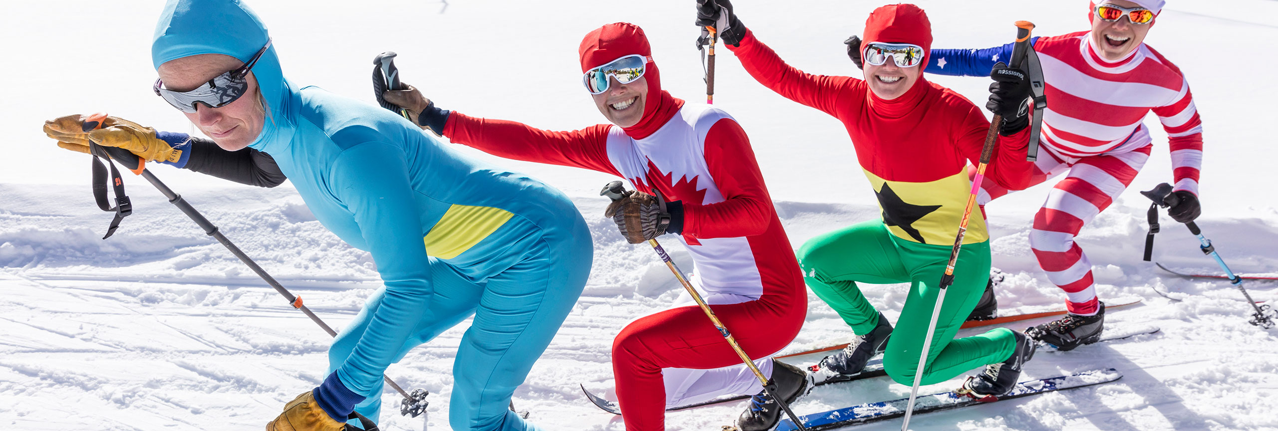 Four people dressed in colorful costumes on cross country skis.