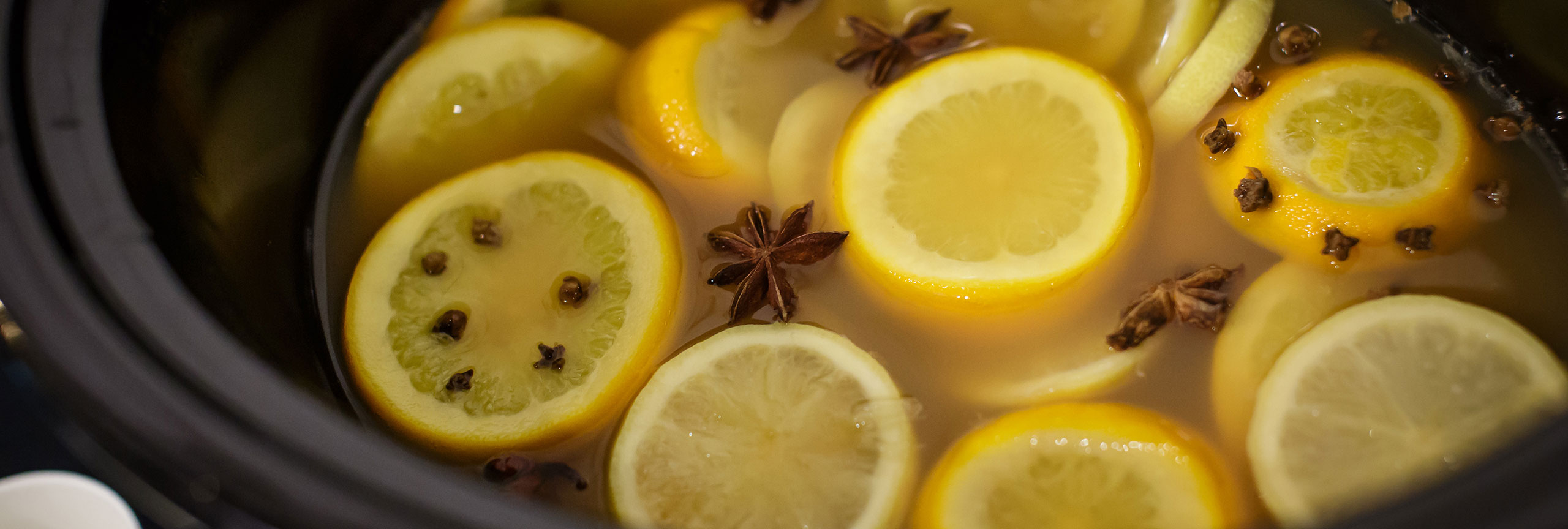 Closeup of lemons and cloves in a pot of wassail.