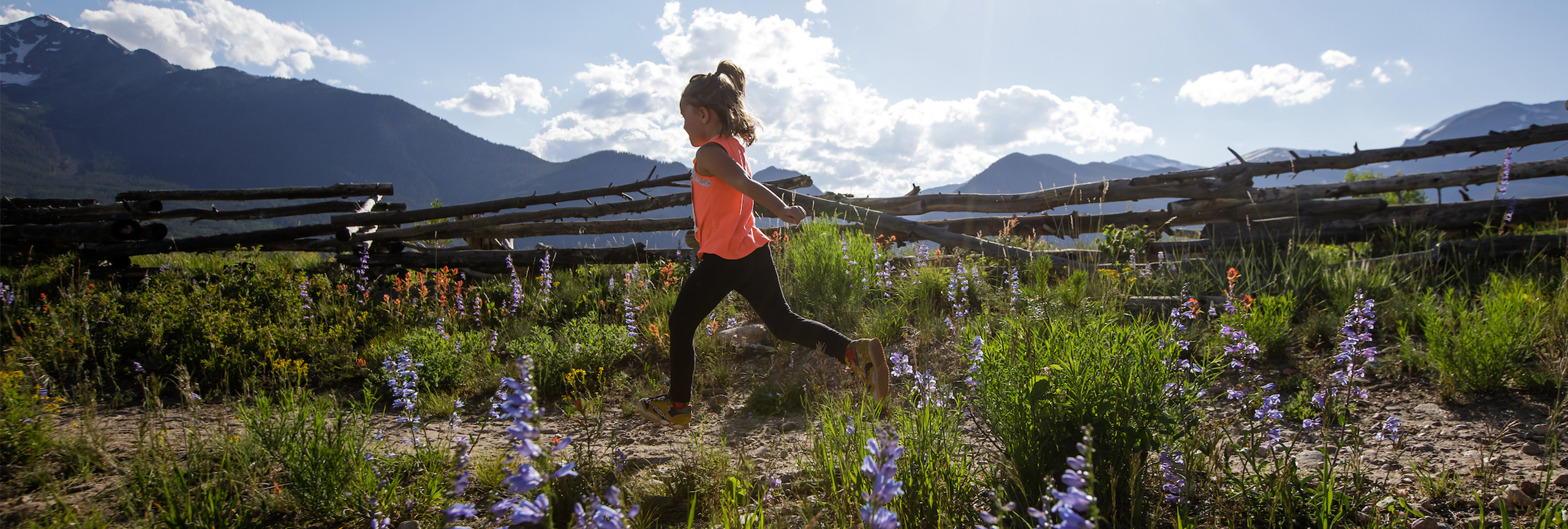 Girl running on trail at Frisco Peninsula with flowers and sun