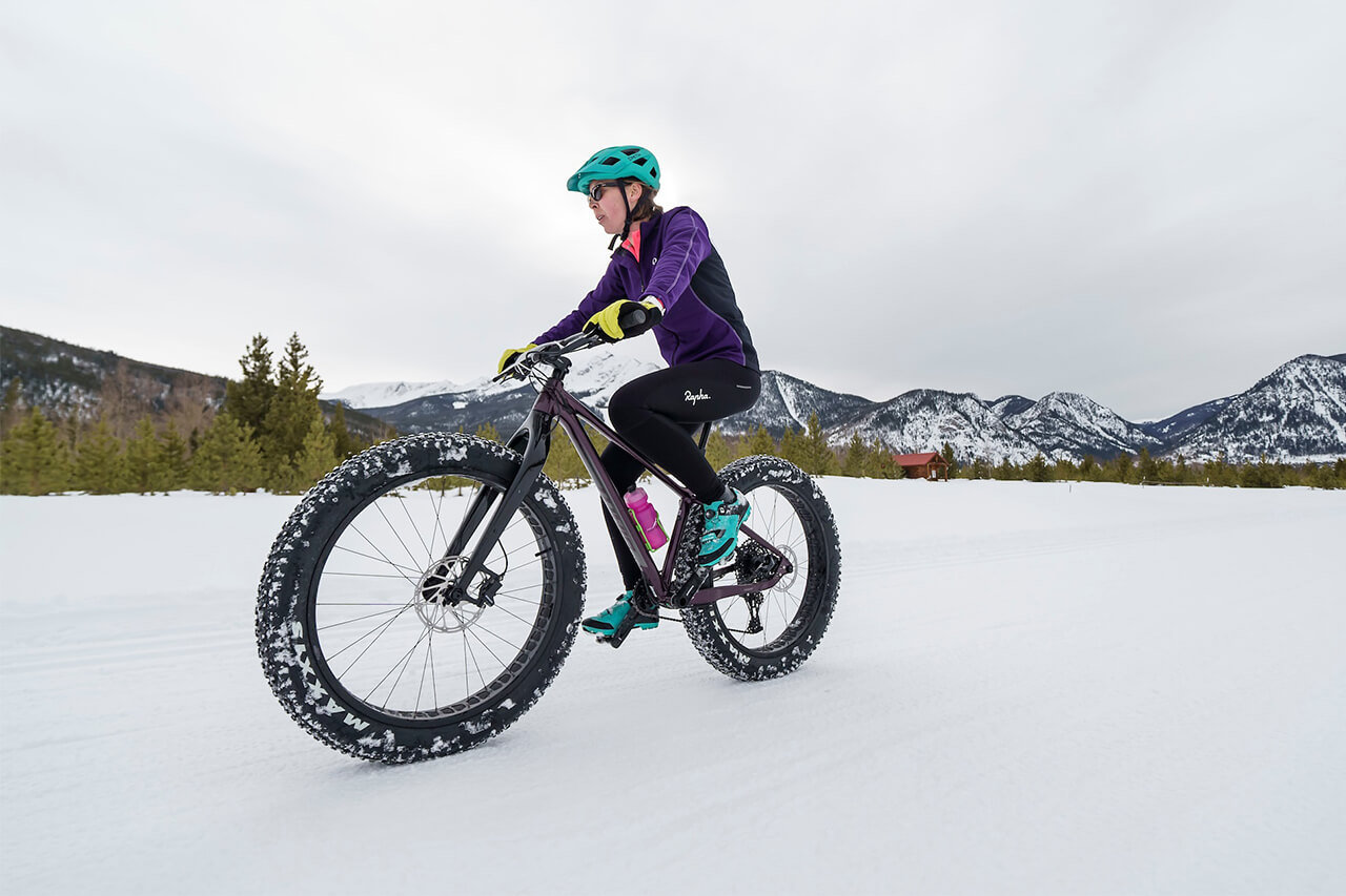 A woman riding a fat-tire bike in the snow.