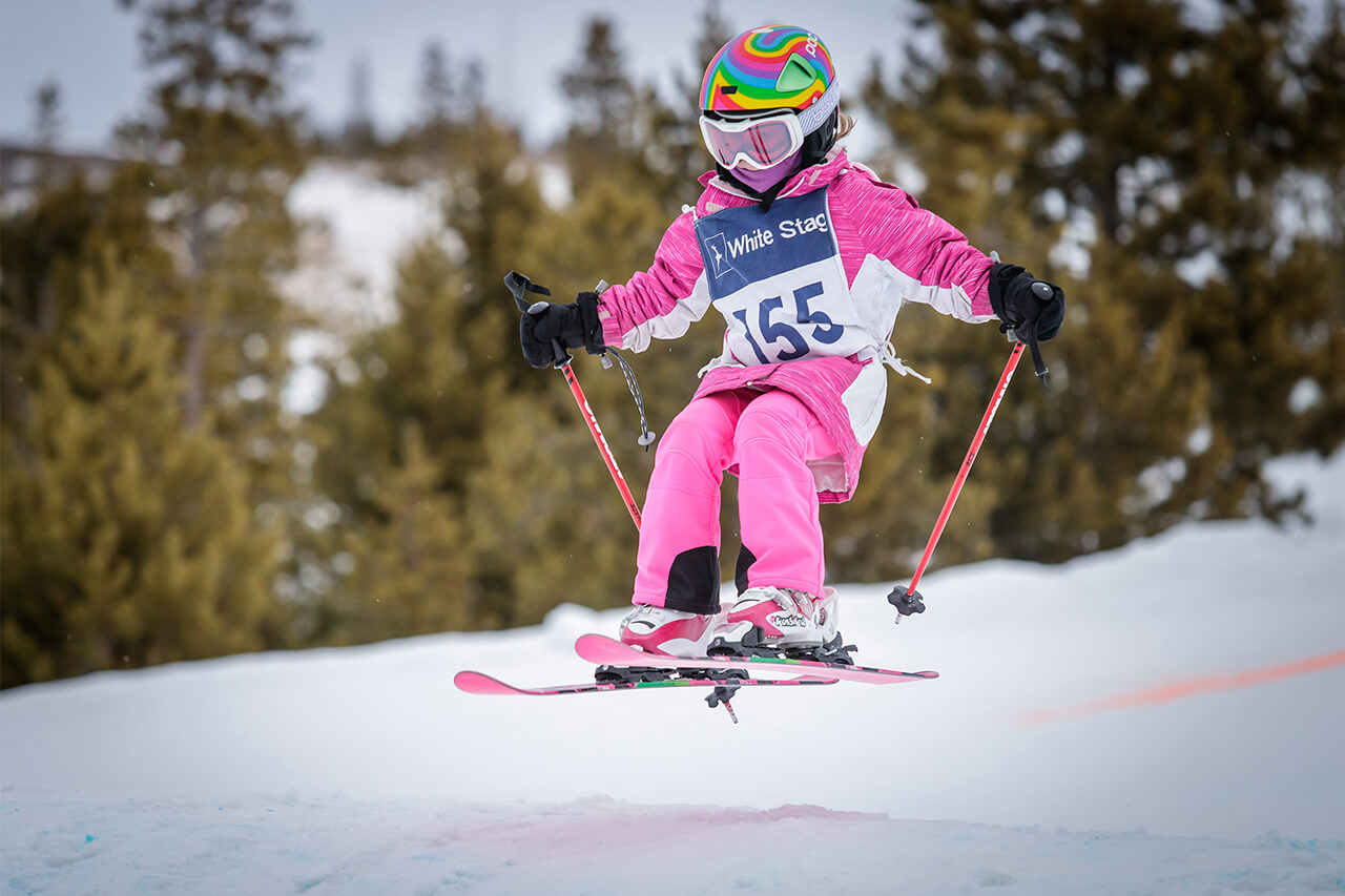 Girl dressed in all pink getting air while skiing at the Frisco Adventure Park