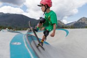 Boy wearing green with red helmet skating in Frisco Skate Park