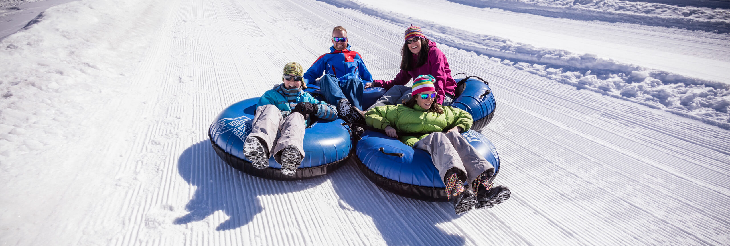 Family of four tubing down hill at Frisco Adventure Park