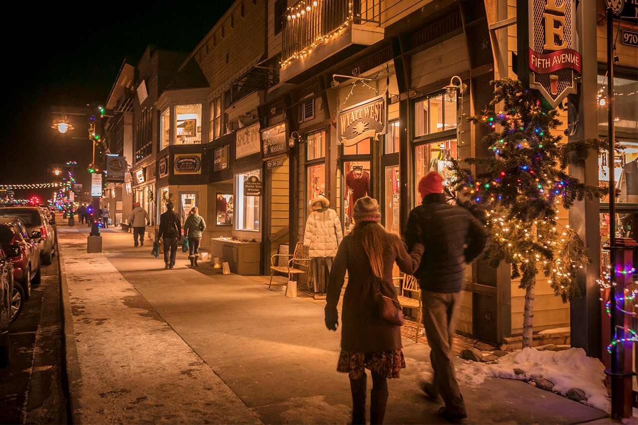 People walking down a festively lit Main Street in the winter.
