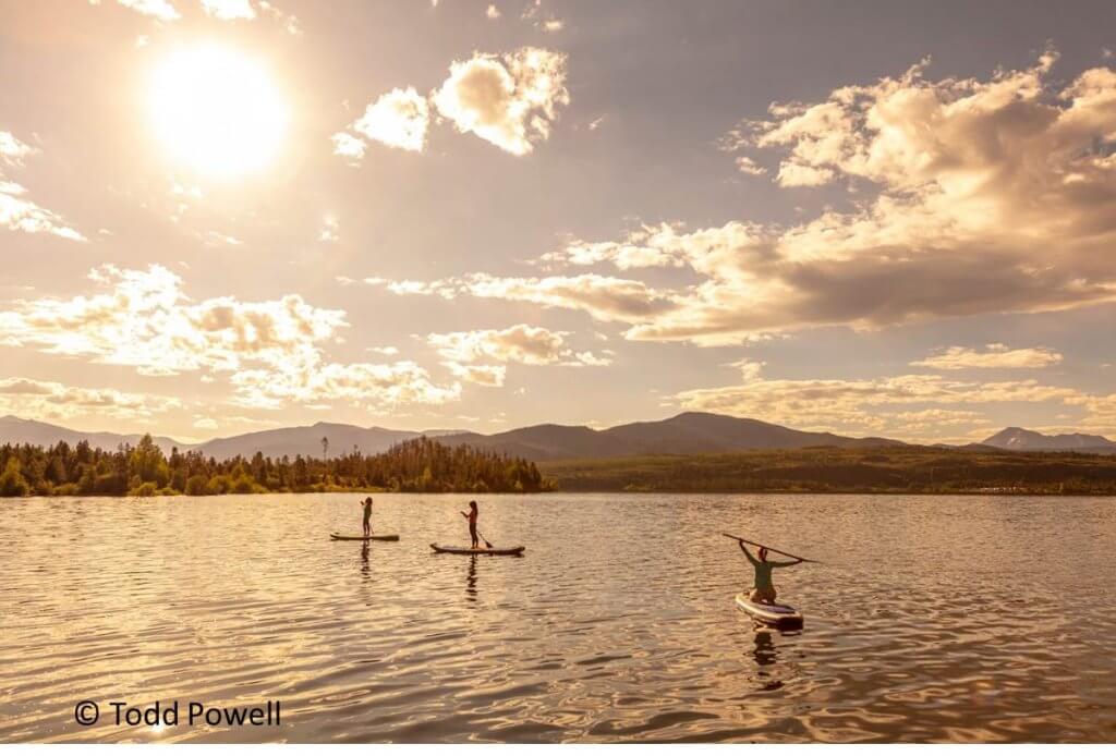 Three stand-up paddle boarders on lake Dillon at sunset.