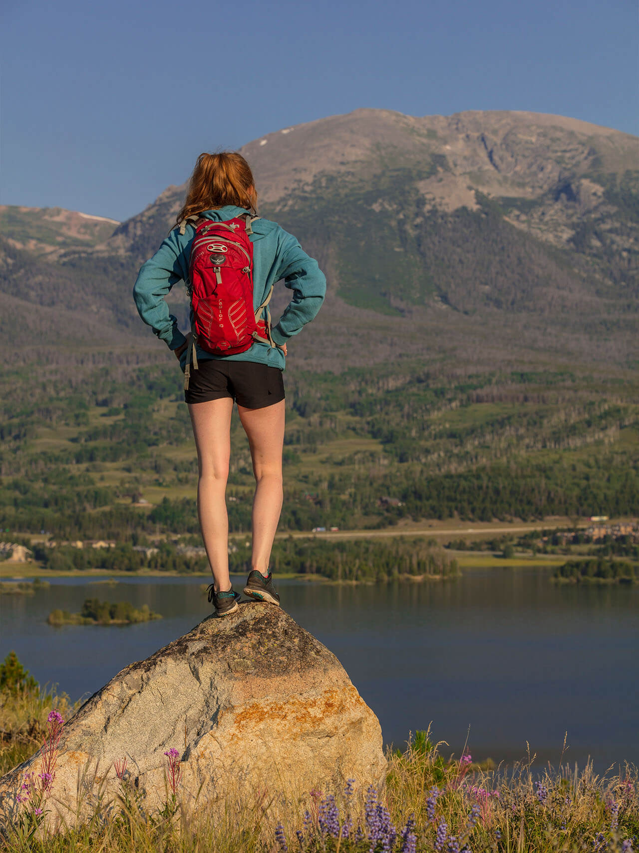 Girl standing on rock looking out at Lake Dillon and Buffalo Mountain.