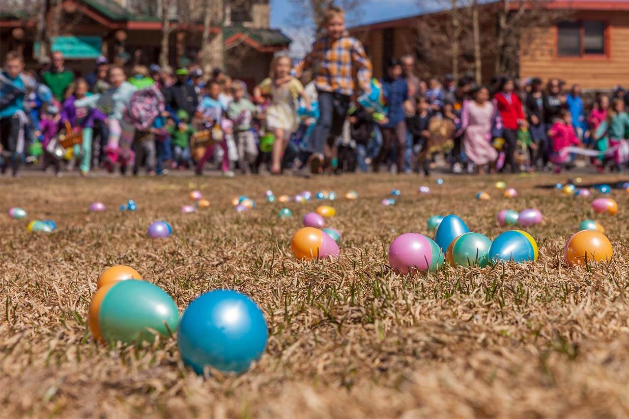 Easter Eggs on grass and kids running at Easter Egg Hunt
