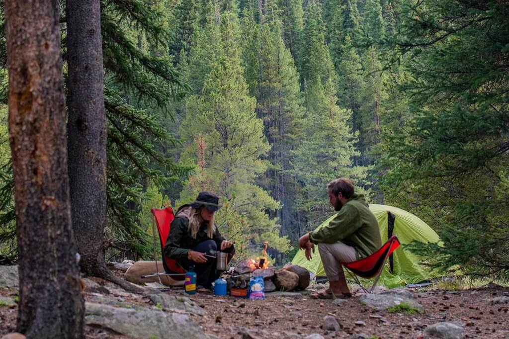 Couple sitting around camp fire in the woods