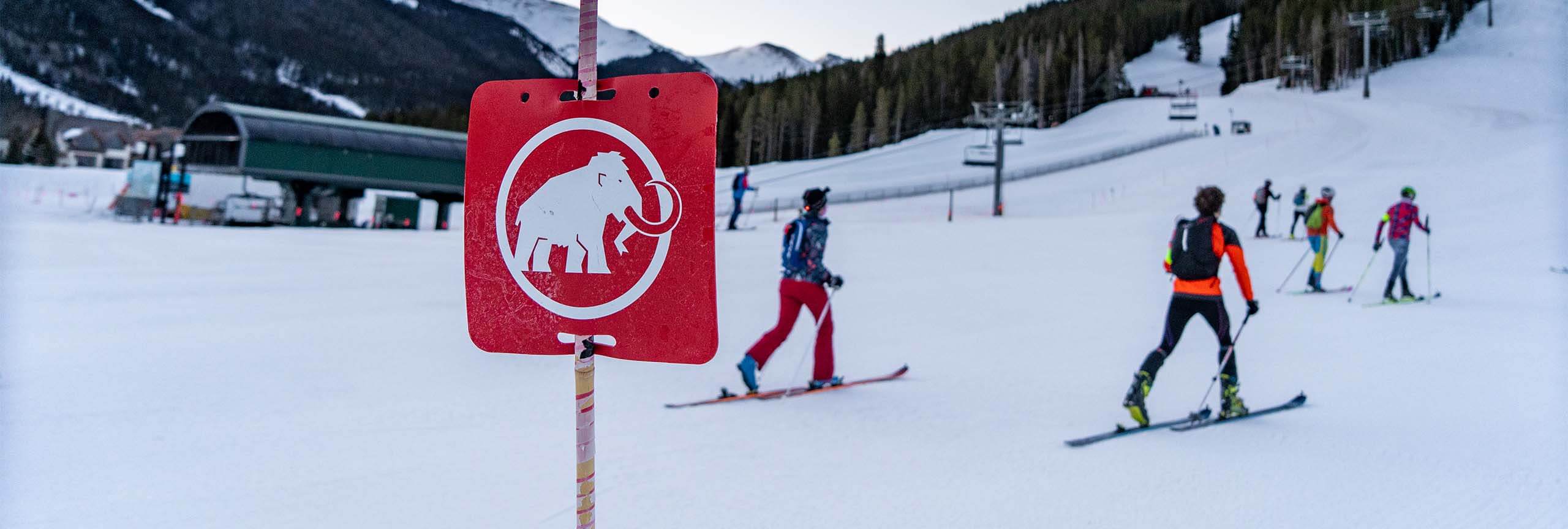 Mammut logo on sign and group of uphill skiers in background