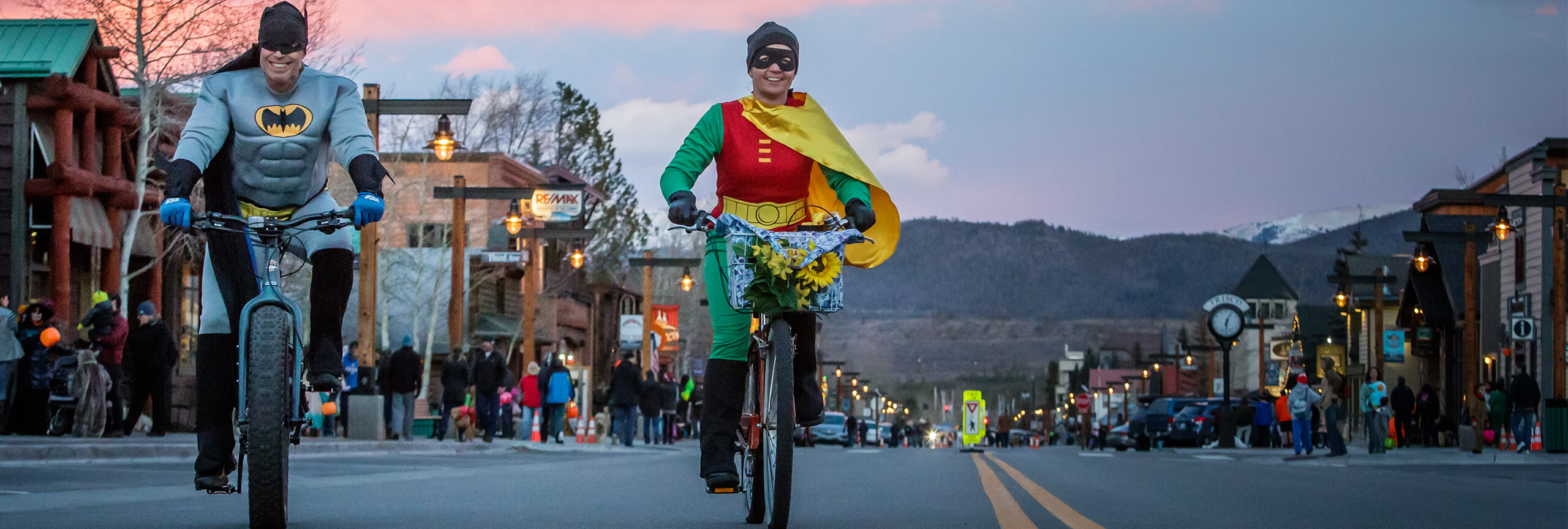 Man and woman dressed as super heroes riding bikes on Frisco Main Street
