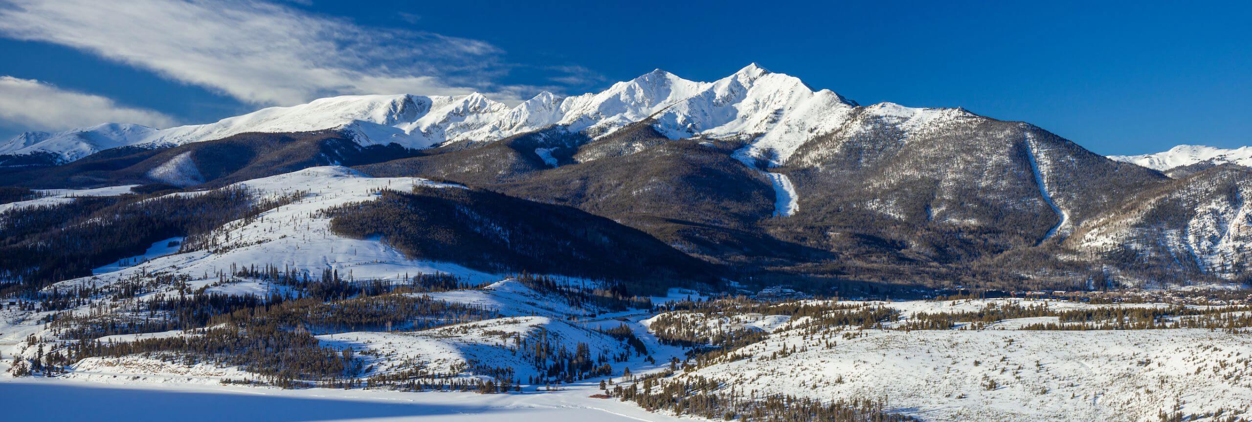 A scenic shot of the Ten Mile Range starting with Mount Royal on the right and ending with Peak two on the left. Peak one sits front and center covered in snow.