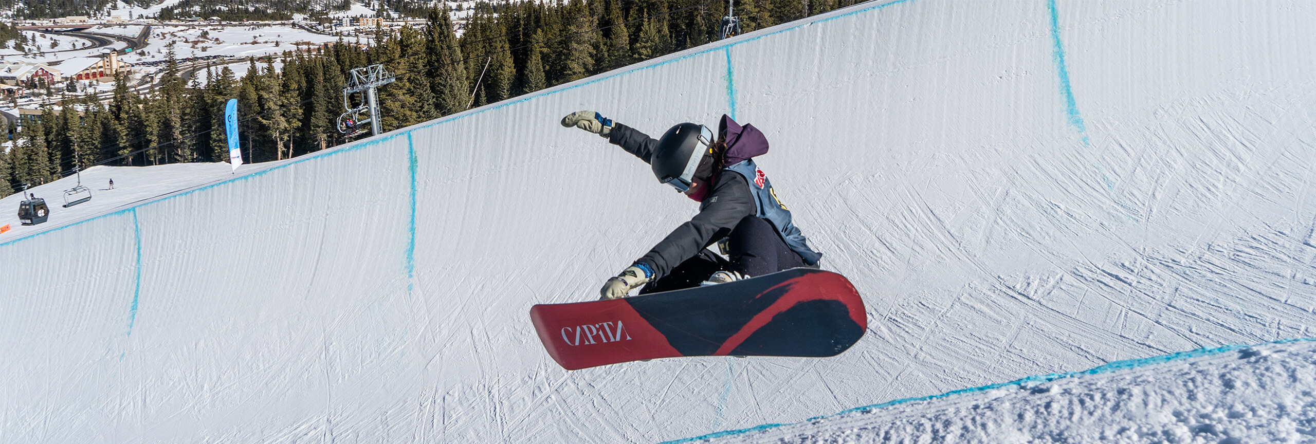 Snowboarder in half pipe grabbing board in USASA Snowboard National Championships at Copper