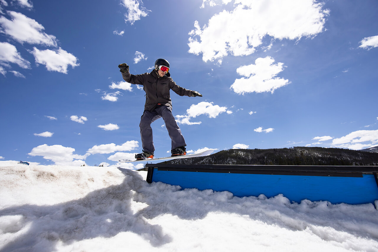 Snowboarder at terrain park above rail