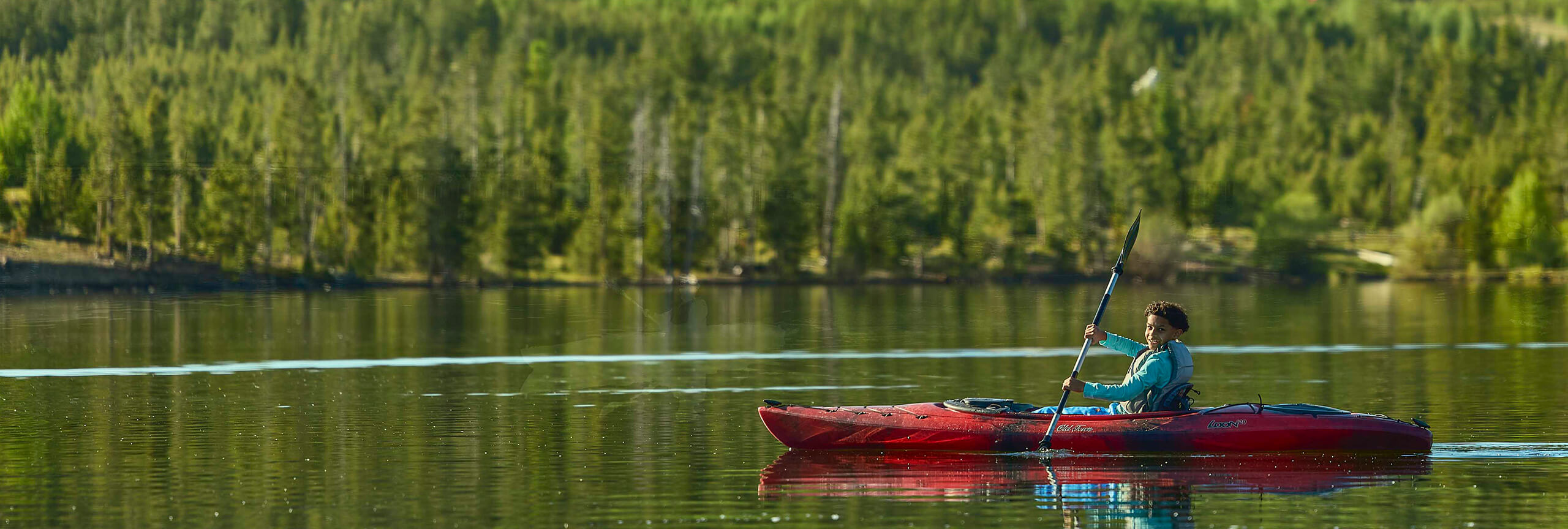 Kayaker on calm water with trees in background